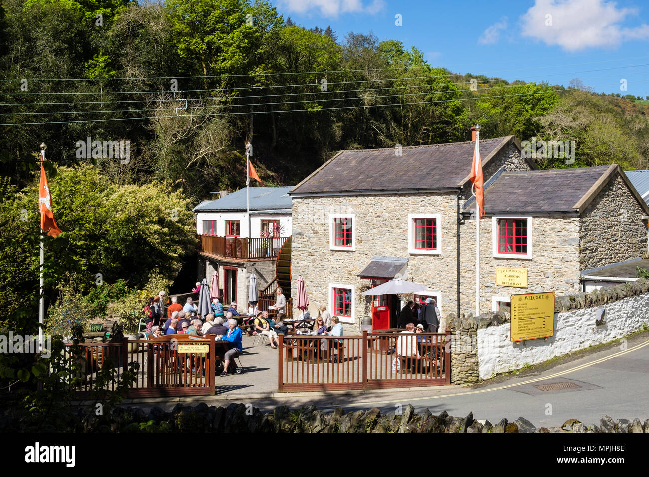 Ballacregga Corn Mill sala da tè e caffè con gente seduta fuori a godersi il sole. Salmone Centro Lago, Laxey, Isola di Man e Isole britanniche Foto Stock
