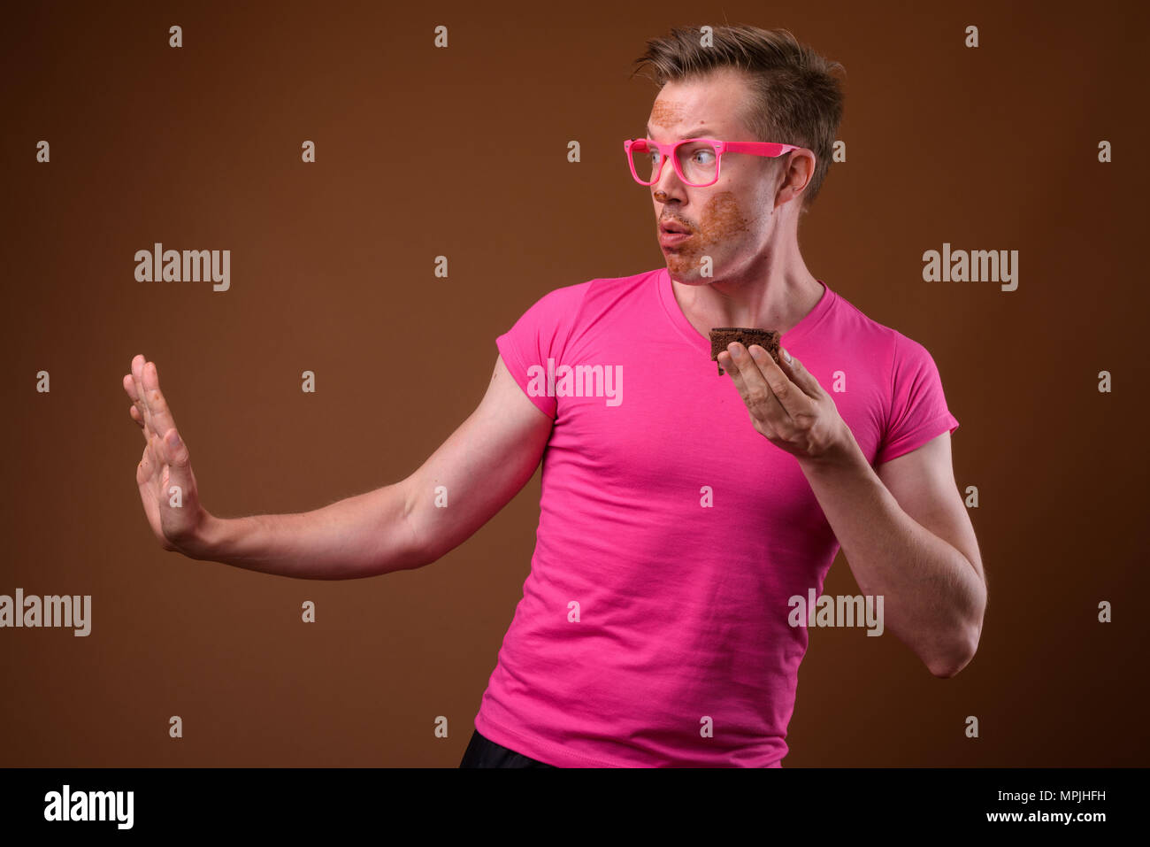 Giovane uomo bello indossare maglia rosa e occhiali contro bro Foto Stock