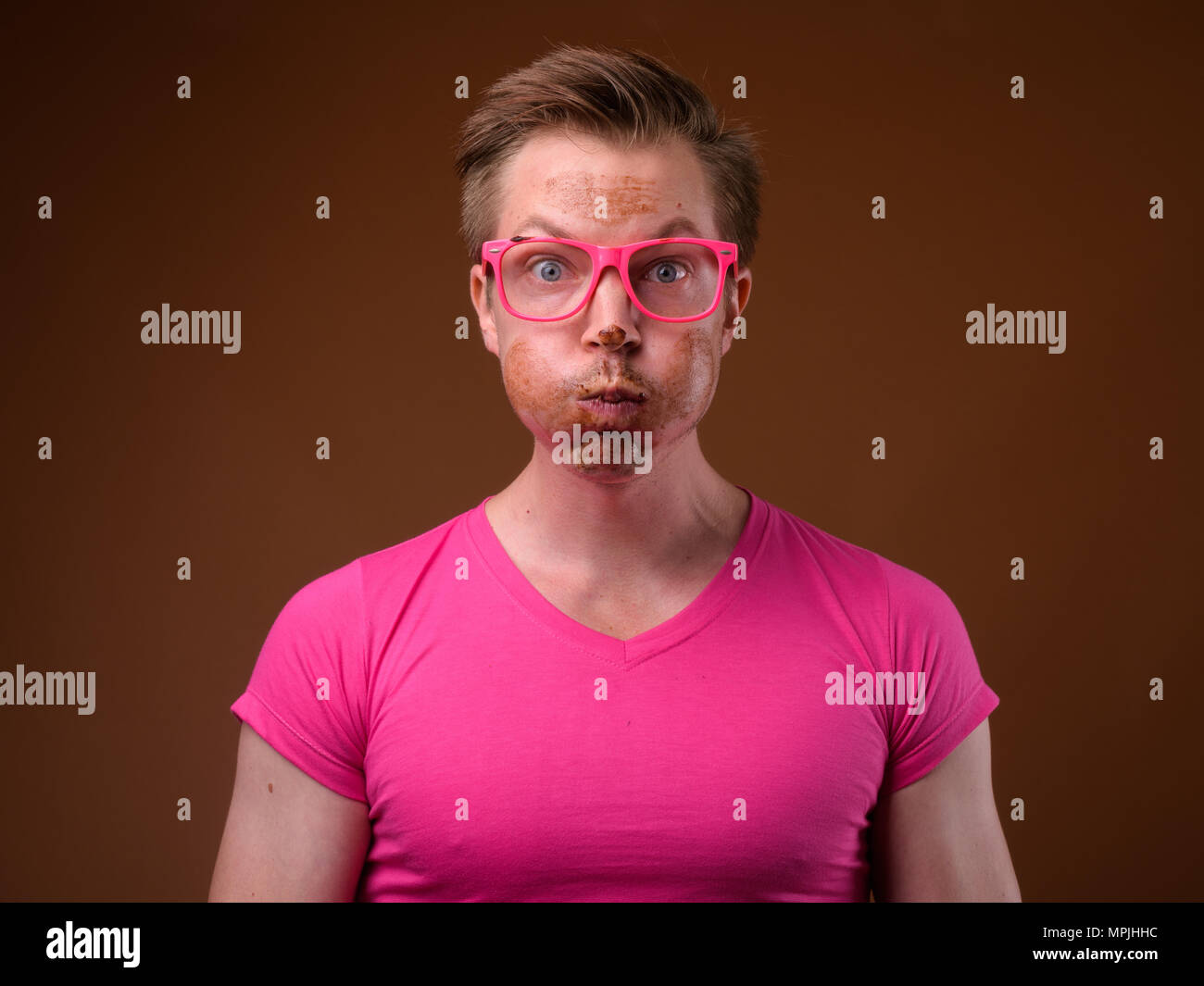 Giovane uomo bello indossare maglia rosa e occhiali contro bro Foto Stock