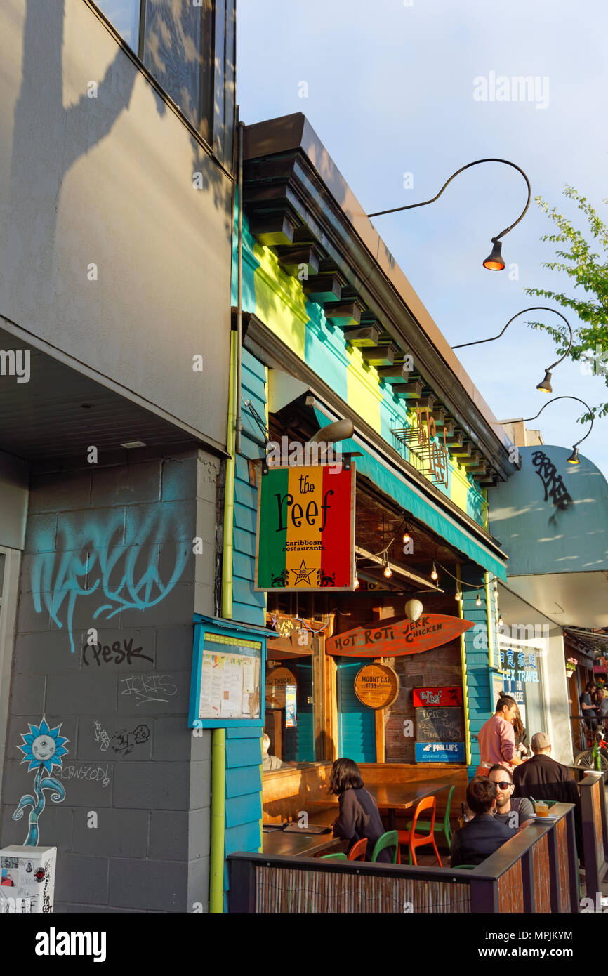 Persone sedute e chiacchierare al di fuori della barriera corallina cibo caraibico ristorante sulla strada principale in Vancouver, BC, Canada Foto Stock