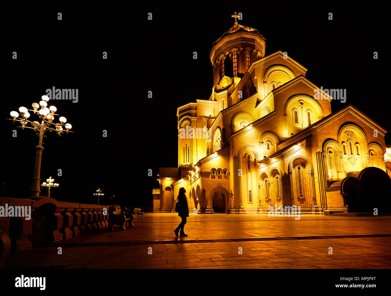Silhouette di donna vicino la Cattedrale della Trinità o Tsminda Sameba di Chiesa di notte a Tbilisi, Georgia Foto Stock