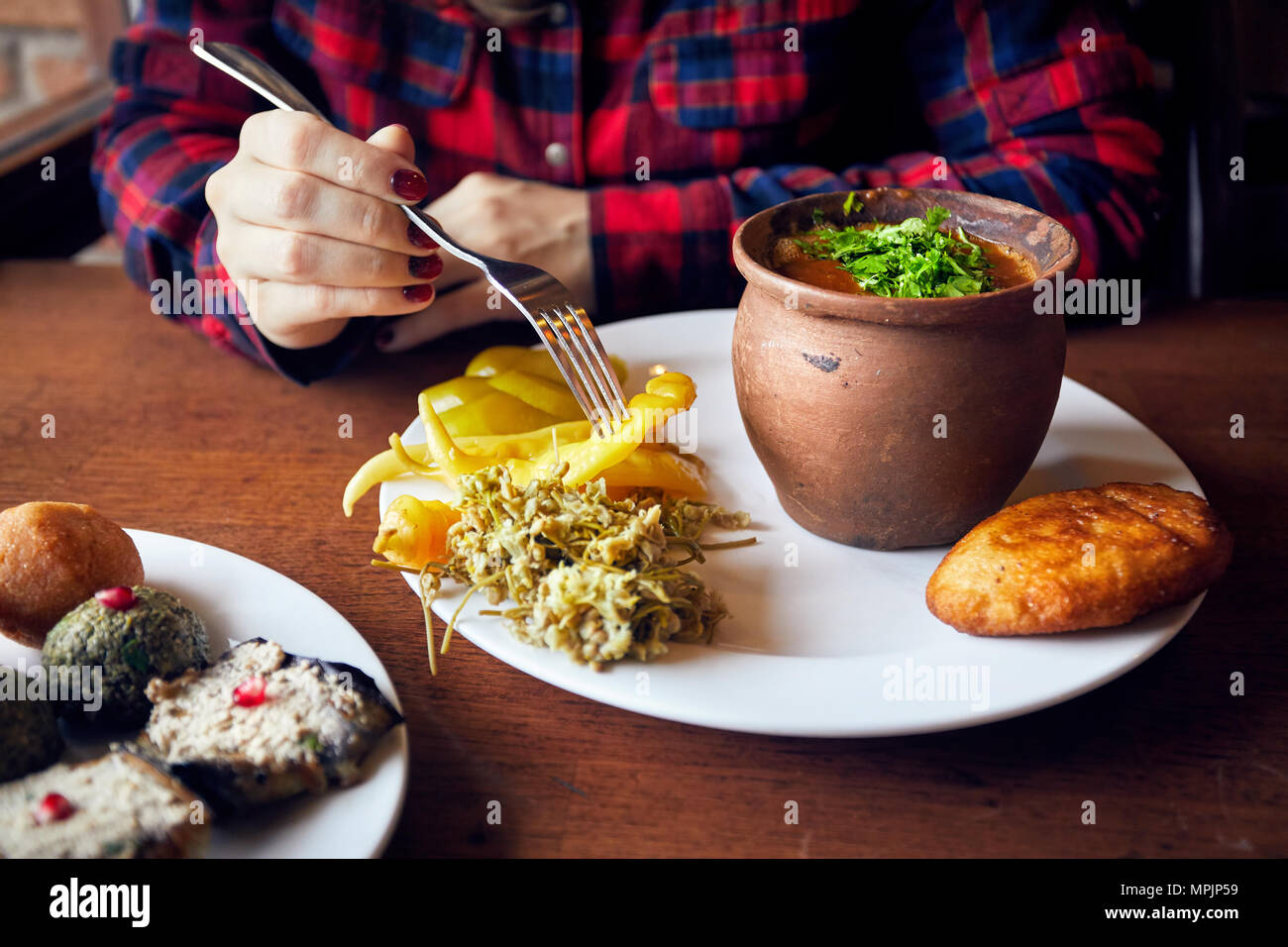 La donna a mangiare fagioli in pentola di creta e serpenti vegetariano pkhali cucina georgiana al ristorante a Tbilisi, Georgia Foto Stock