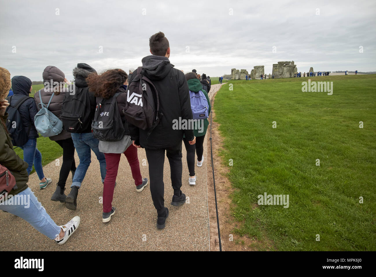 Scuola tour visita di un gruppo di giovani studenti a piedi fino a Stonehenge Wiltshire, Inghilterra Regno Unito Foto Stock