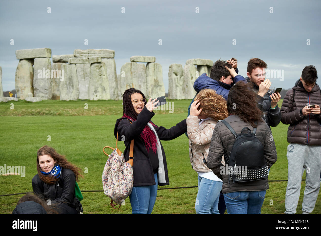 Tour del gruppo di giovani studenti prendere selfies a Stonehenge Wiltshire, Inghilterra Regno Unito Foto Stock