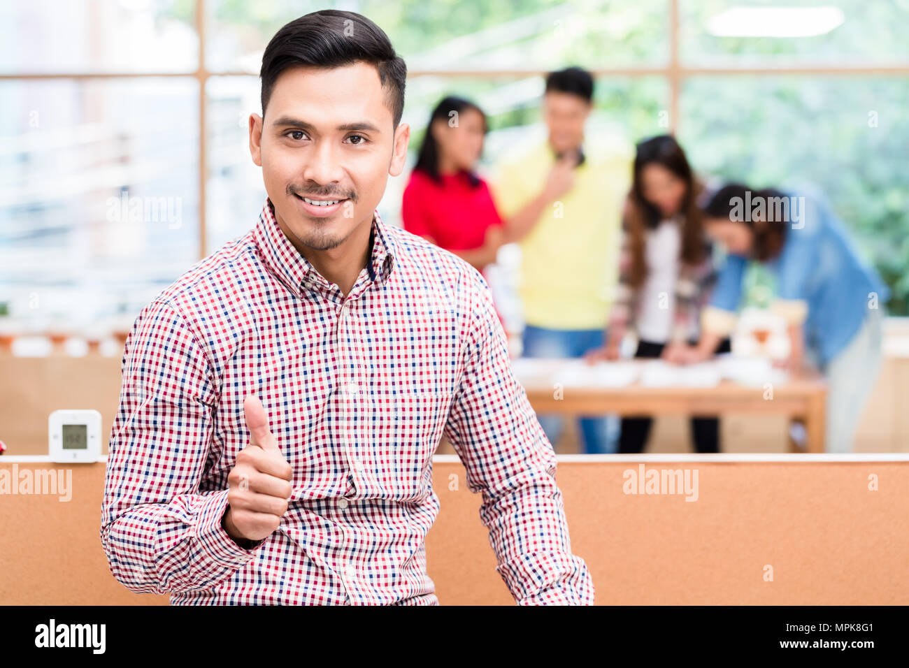 Ritratto di giovane fiducioso dipendente Asiatica che mostra il pollice in alto Foto Stock