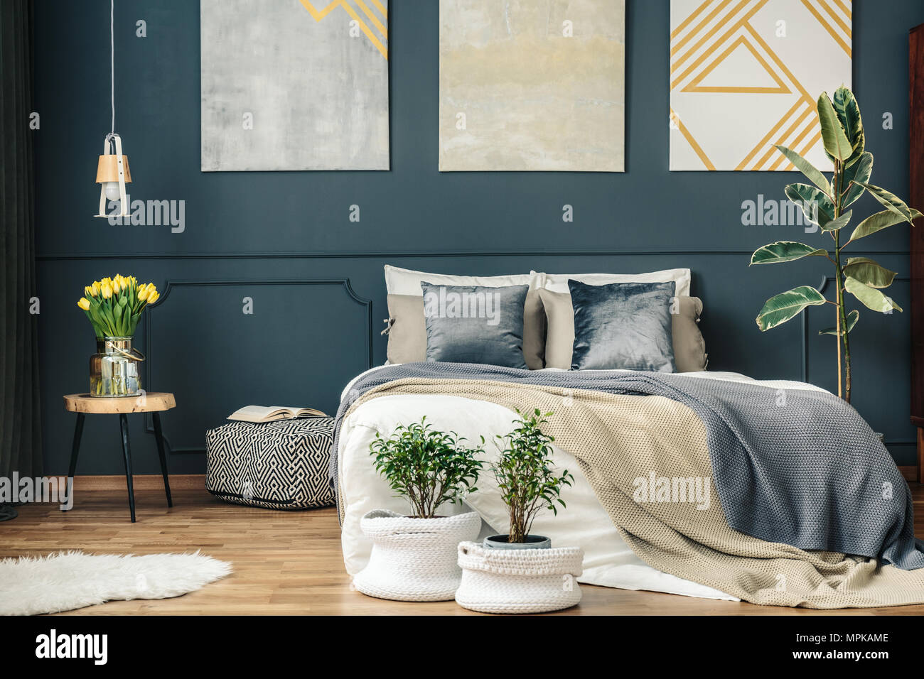 Grande e comodo letto sotto il poster sulla parete scura con stampaggio e  tra piante in camera da letto interno Foto stock - Alamy
