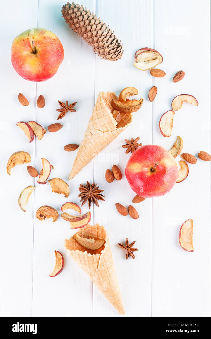 Autunno still life - waffle tazze, pigne secche Mele sulla lavagna bianca vista superiore Foto Stock