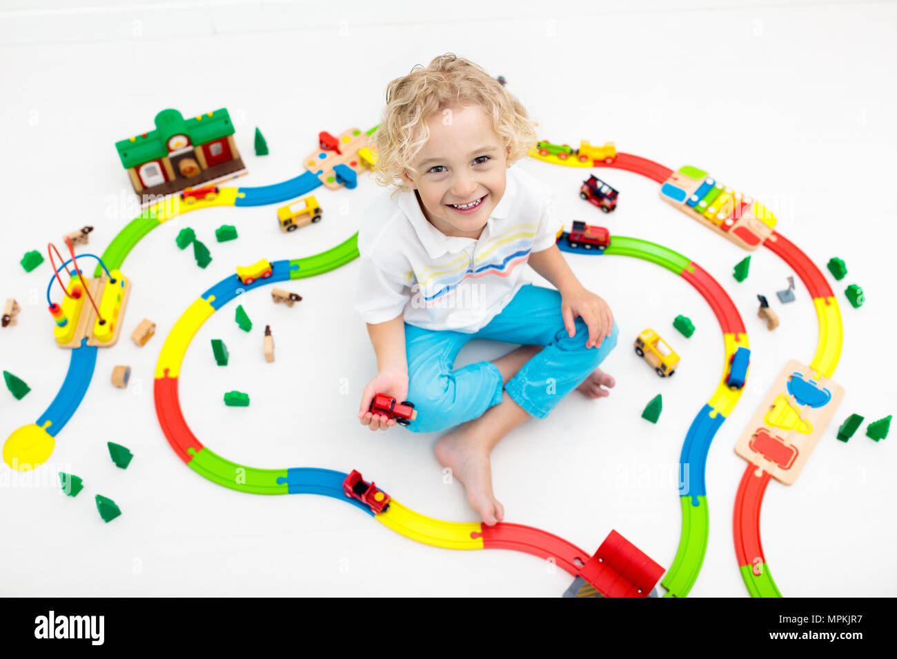 Bambini a giocare con il trenino ferrovia. Bambini che giocano con colorati rainbow treni di legno. Giocattoli per bambino. Edificio Preschooler rail road a casa o da Foto Stock