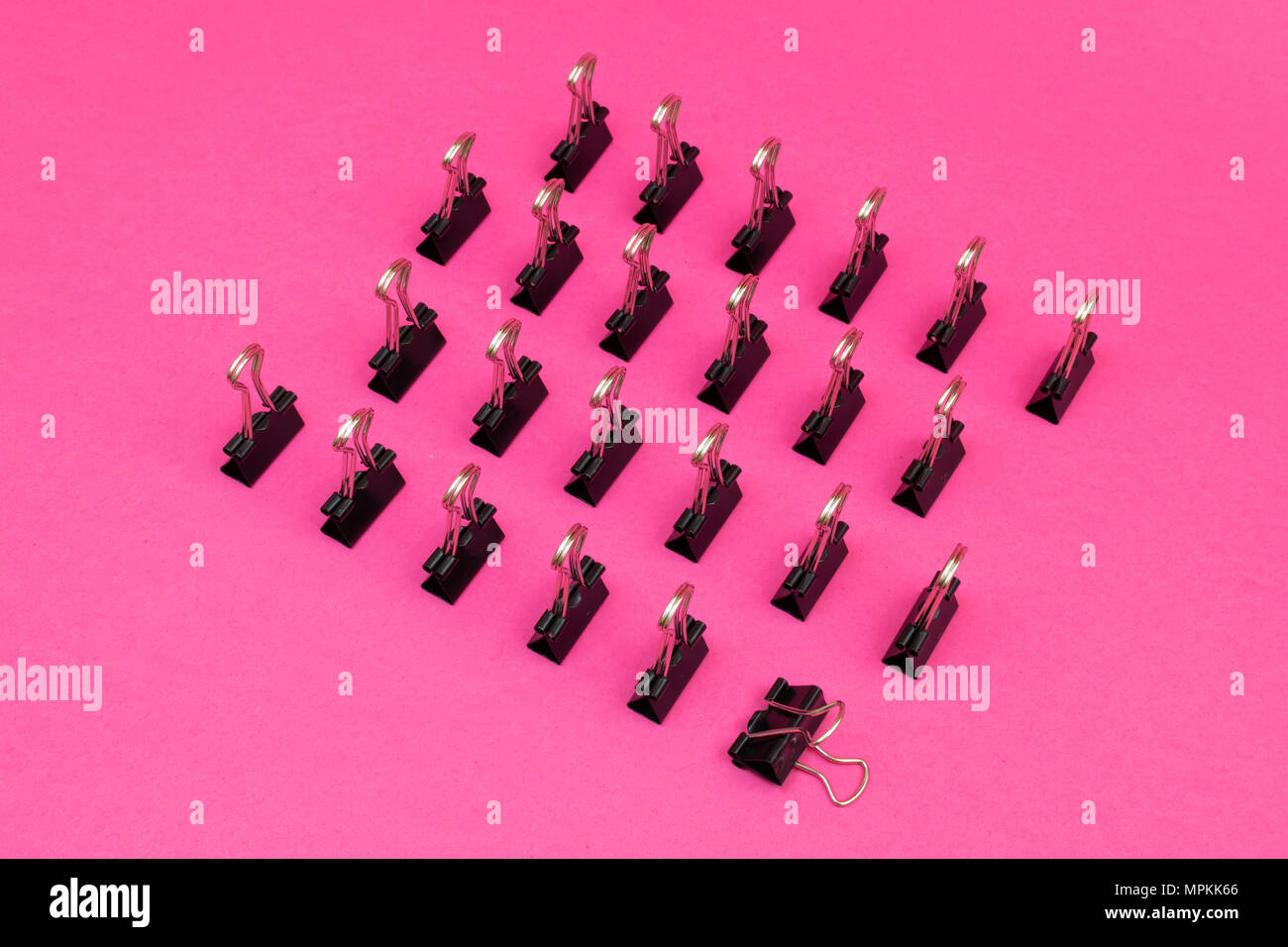 Le graffe di legante schierati in piedi nel modello minimalista sulla colorata di rosa sfondo magenta Foto Stock