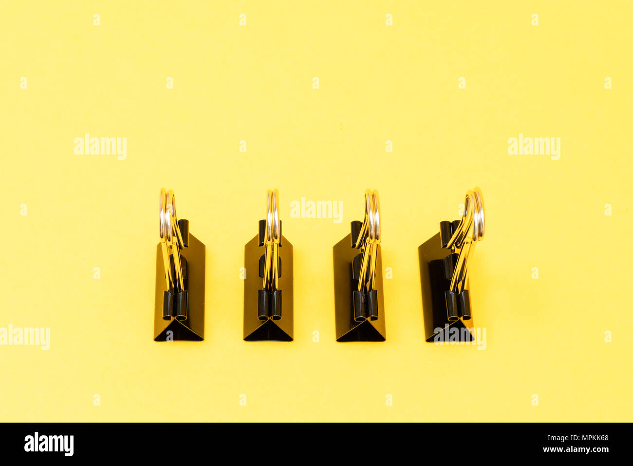 Le graffe di legante schierati in piedi nel modello minimalista colorato su sfondo giallo Foto Stock