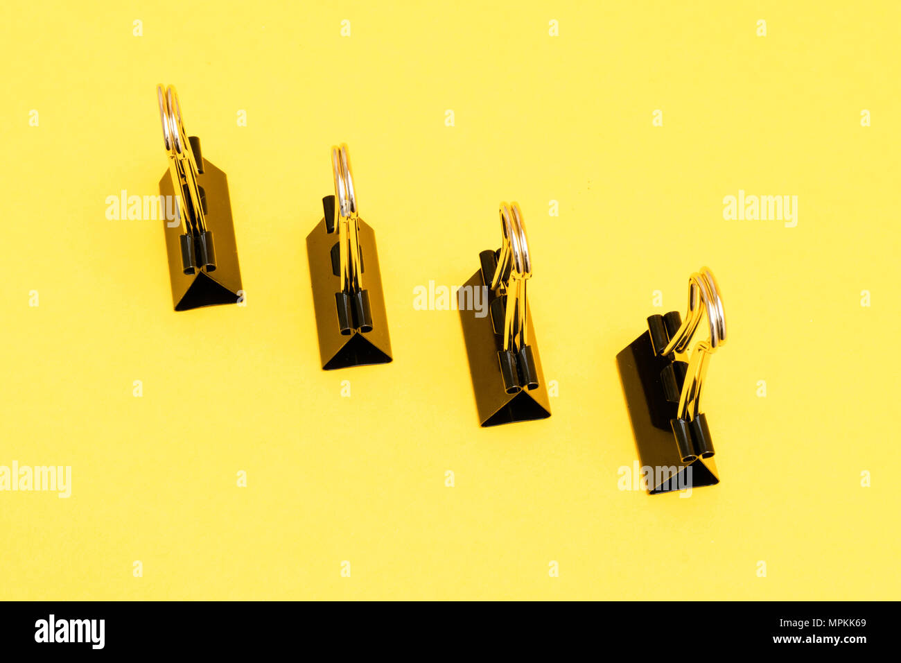 Le graffe di legante schierati nel modello minimalista colorato su sfondo giallo Foto Stock