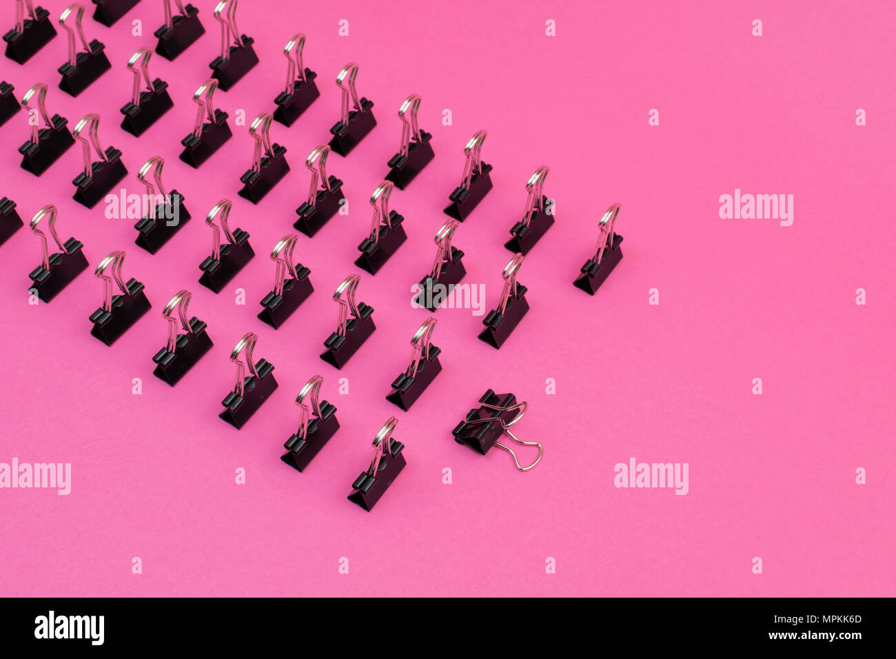 Le graffe di legante schierati in piedi nel modello minimalista sulla colorata di rosa sfondo magenta Foto Stock