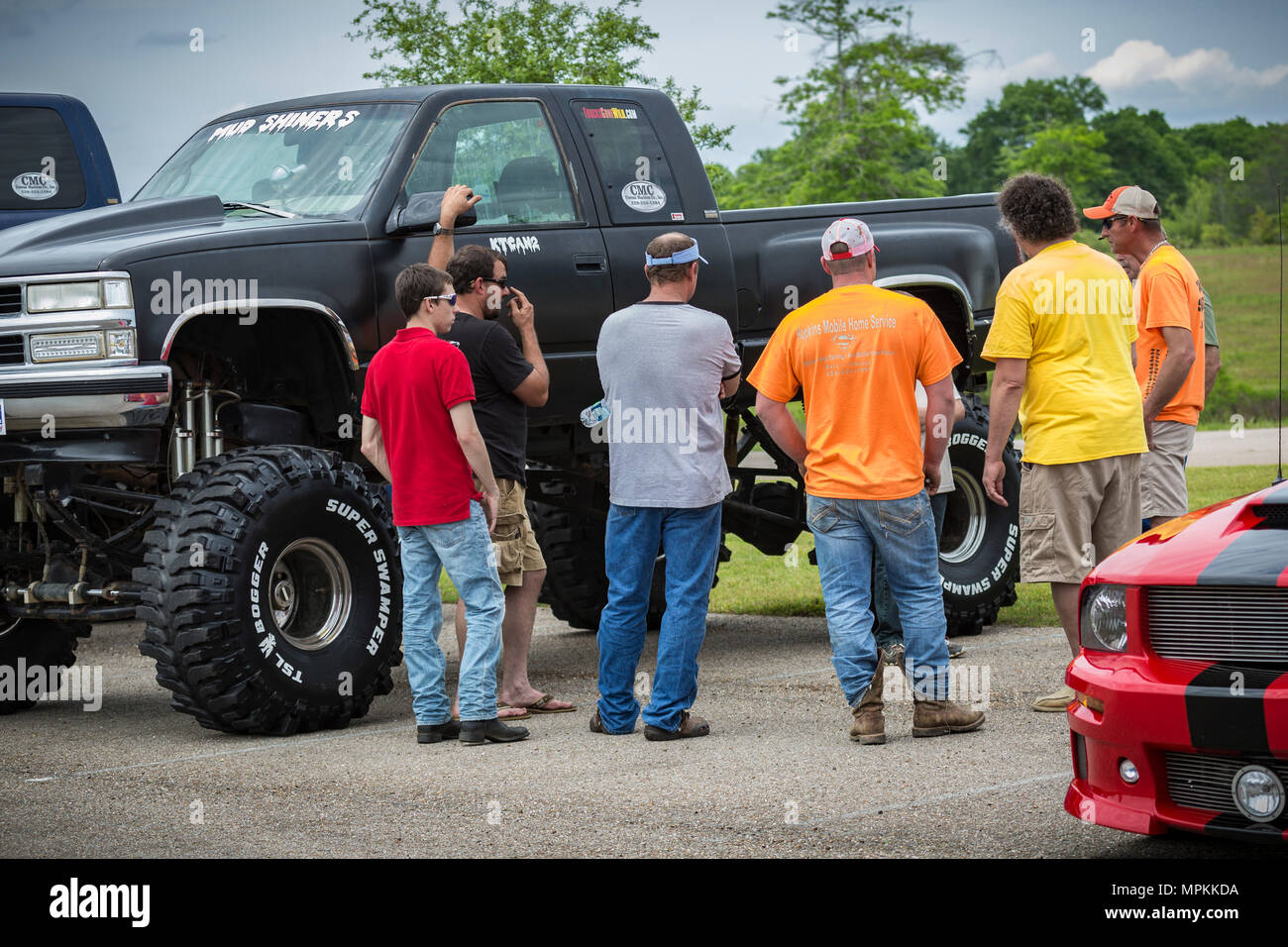 Uomini che ammirano un camion personalizzato a quattro ruote motrici in un evento di raccolta fondi di auto show alla Chiesa di Crosspoint a Gulfport, Mississippi Foto Stock
