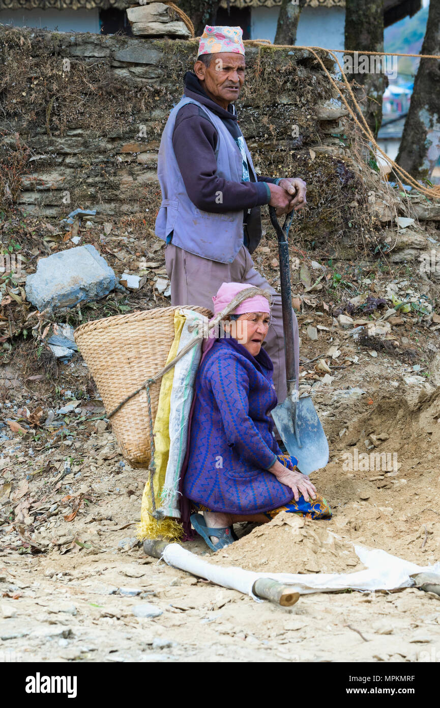 Nepalesi per l uomo e la donna che trasportano le pietre per la costruzione di strade, Dhampus villaggio di montagna, Nepal Foto Stock