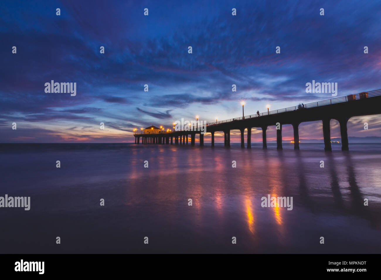 Lunga esposizione shot colorata del Cielo e nubi su Manhattan Beach Pier dopo il tramonto liscio con lavaggio onde sulla spiaggia, Manhattan Beach, Califo Foto Stock