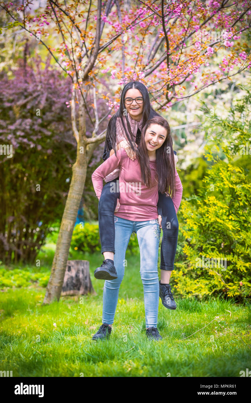 Due graziose sorelle ragazze abbracci e divertirsi insieme, indossando vestiti alla moda, emozioni positive. Foto Stock
