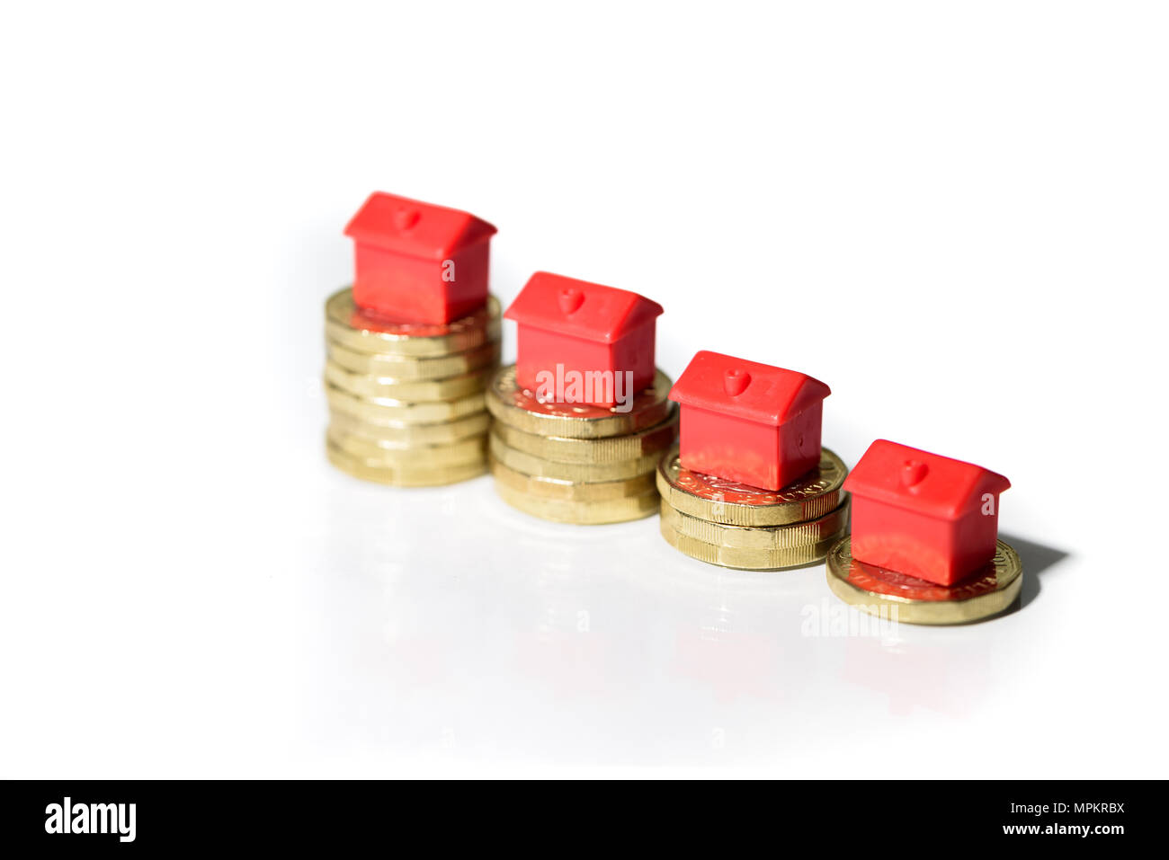Case in miniatura in appoggio sulla nuova moneta sterlina pile concetto per la proprietà Scala, ipotecari e immobiliari Investimenti Foto Stock