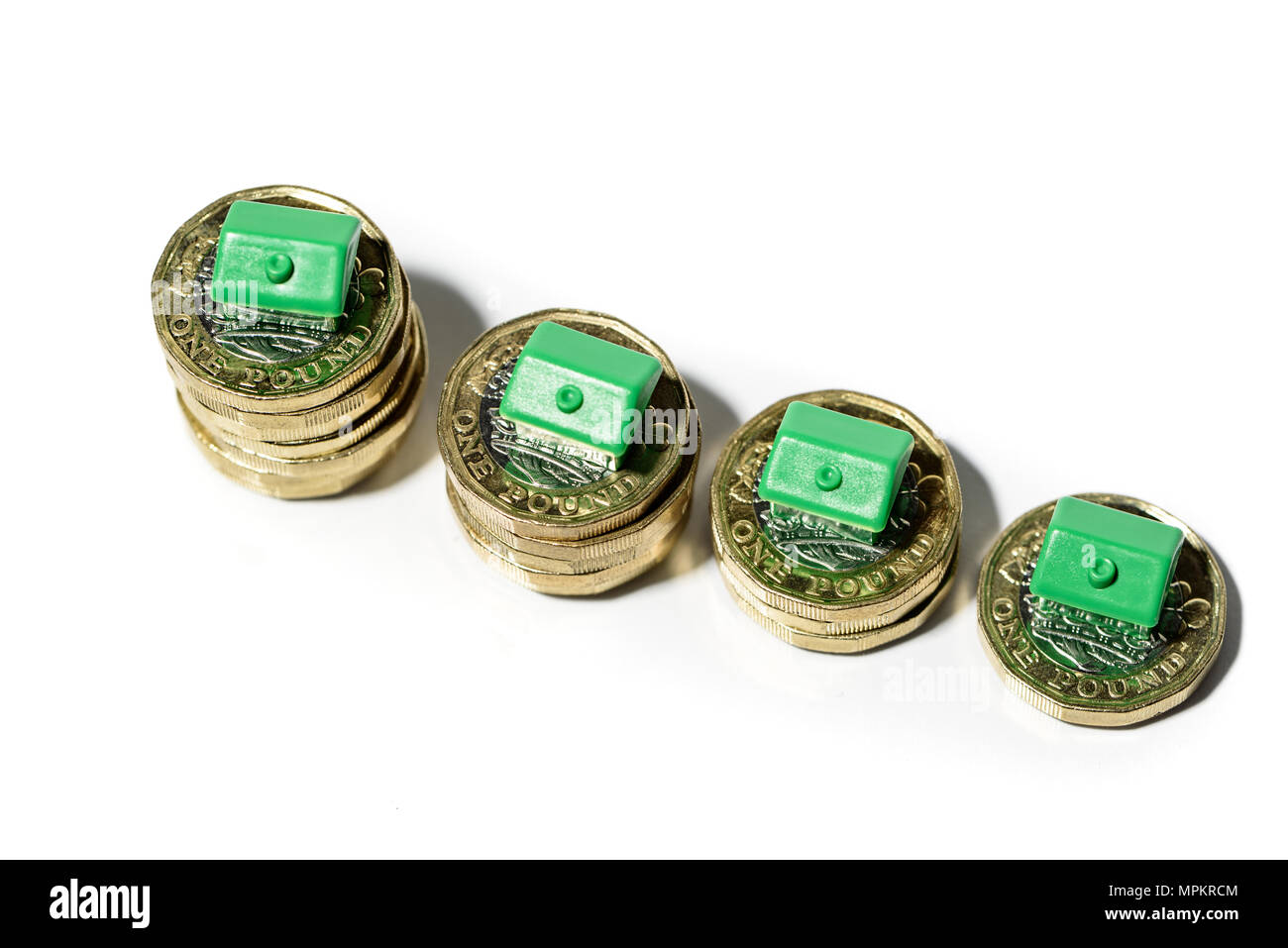 Case in miniatura in appoggio sulla nuova moneta sterlina pile concetto per la proprietà Scala, ipotecari e immobiliari Investimenti Foto Stock
