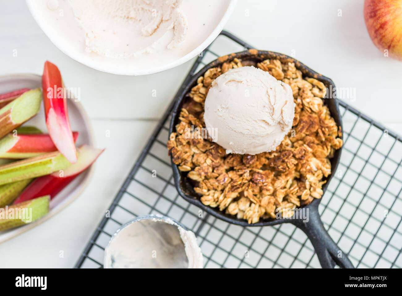 Cucinato in casa di rabarbaro e apple crumble con farina di avena e gelato alla vaniglia nel ferro padelle Foto Stock