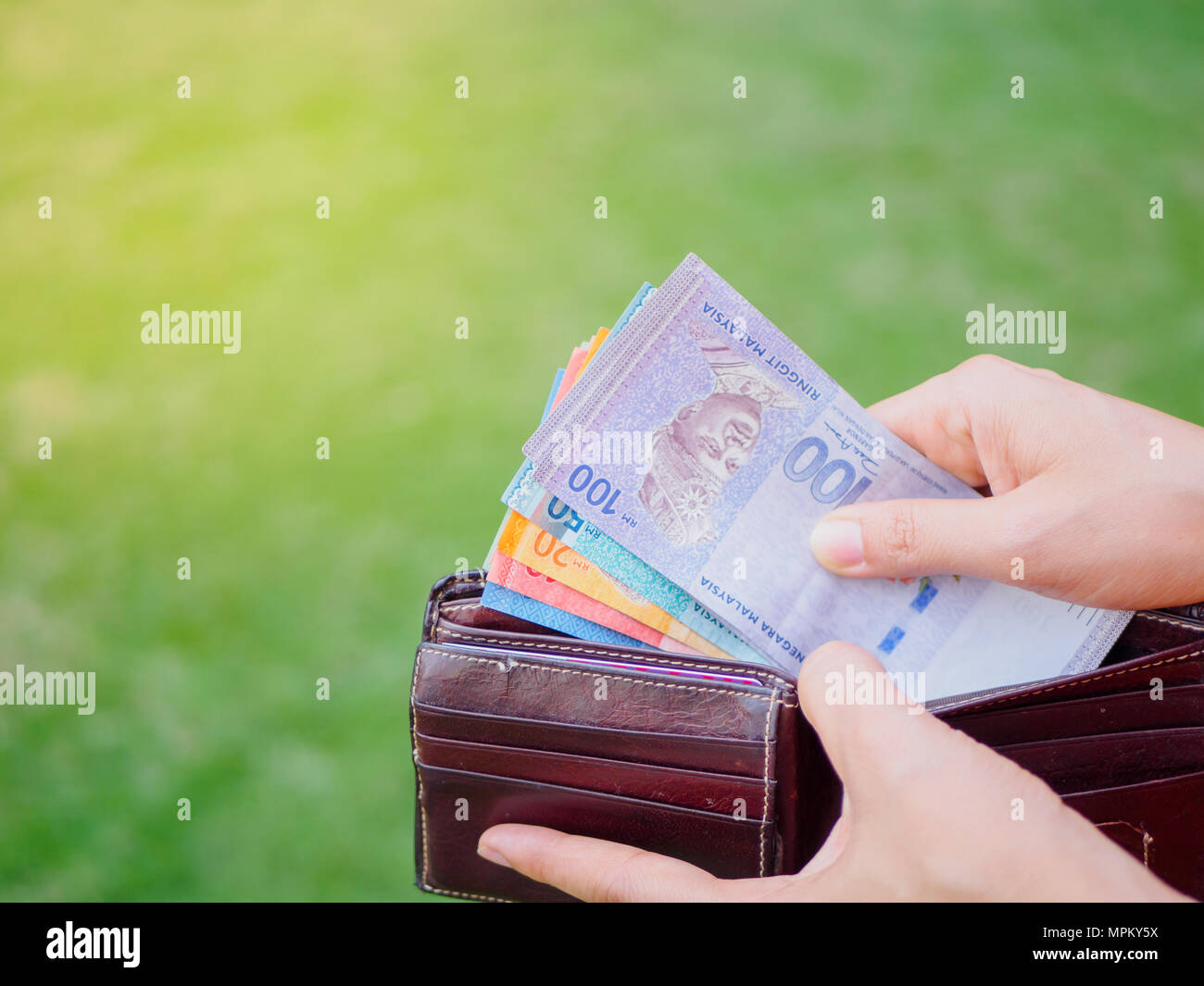 Le donne le mani tenendo fuori i soldi della Malaysia ringgit dal  portafoglio sul verde del campo di erba Foto stock - Alamy