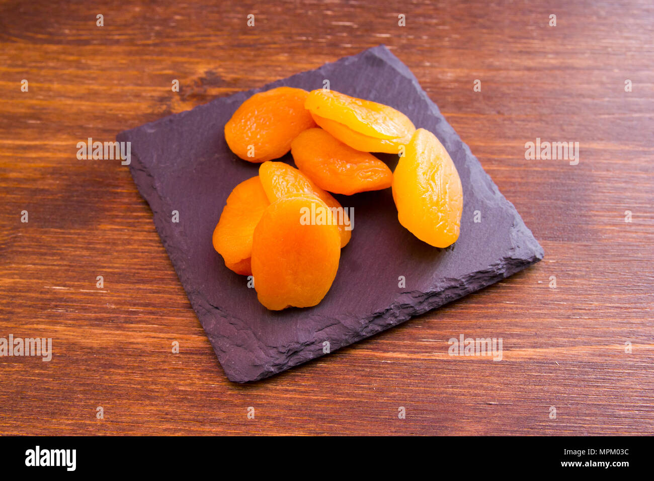 Albicocche snocciolate sul vassoio di ardesia su un tavolo di legno Foto Stock