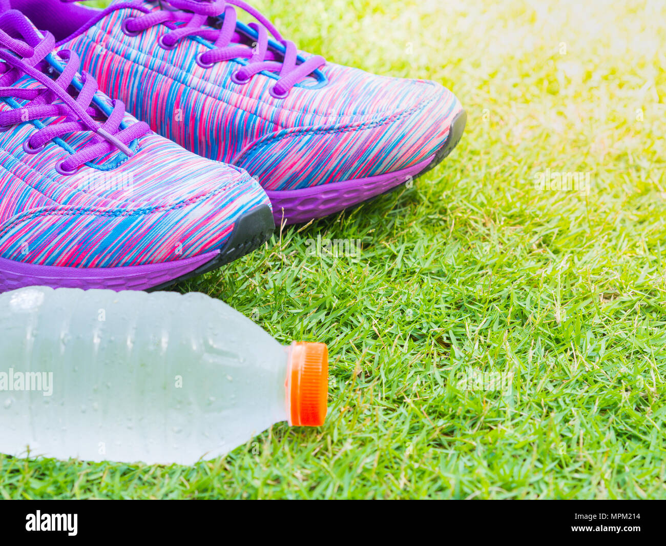 Coppia di rosa scarpe di sport e di acqua in bottiglia su erba verde campo. Nella foresta di sfondo o park trail. Accessori per lo sport in esecuzione Foto stock Alamy