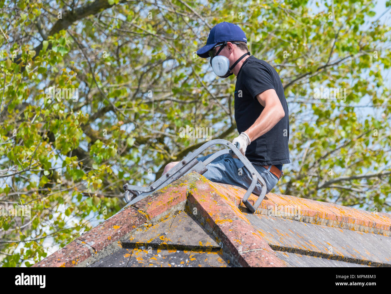 L'uomo la spruzzatura di un tetto indossando un respiratore di protezione maschera, NEL REGNO UNITO. Foto Stock