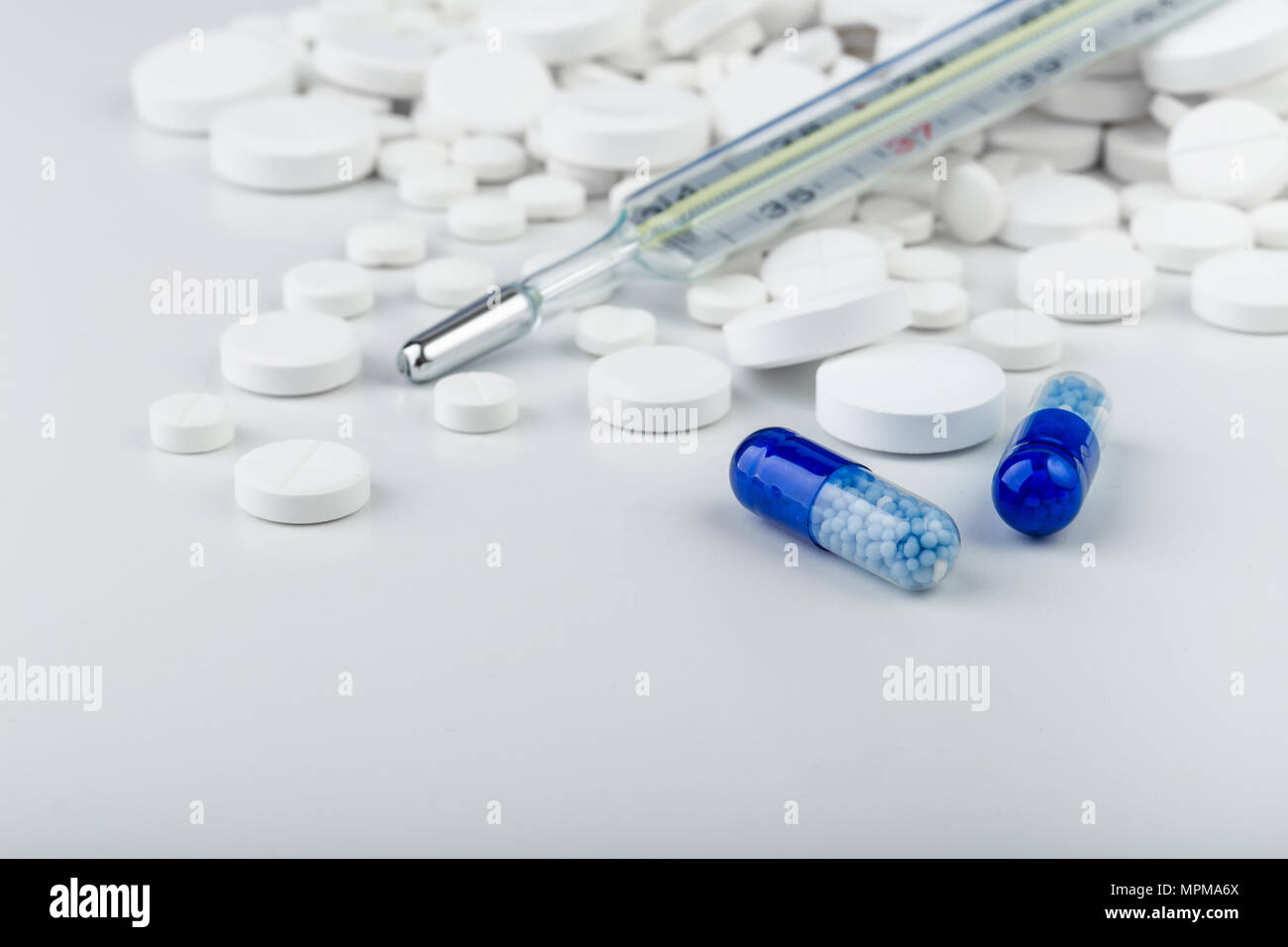 Grappolo di compresse di colore bianco con blu pillole e termometro. Sparse in pillole.messa a fuoco selettiva. Foto Stock