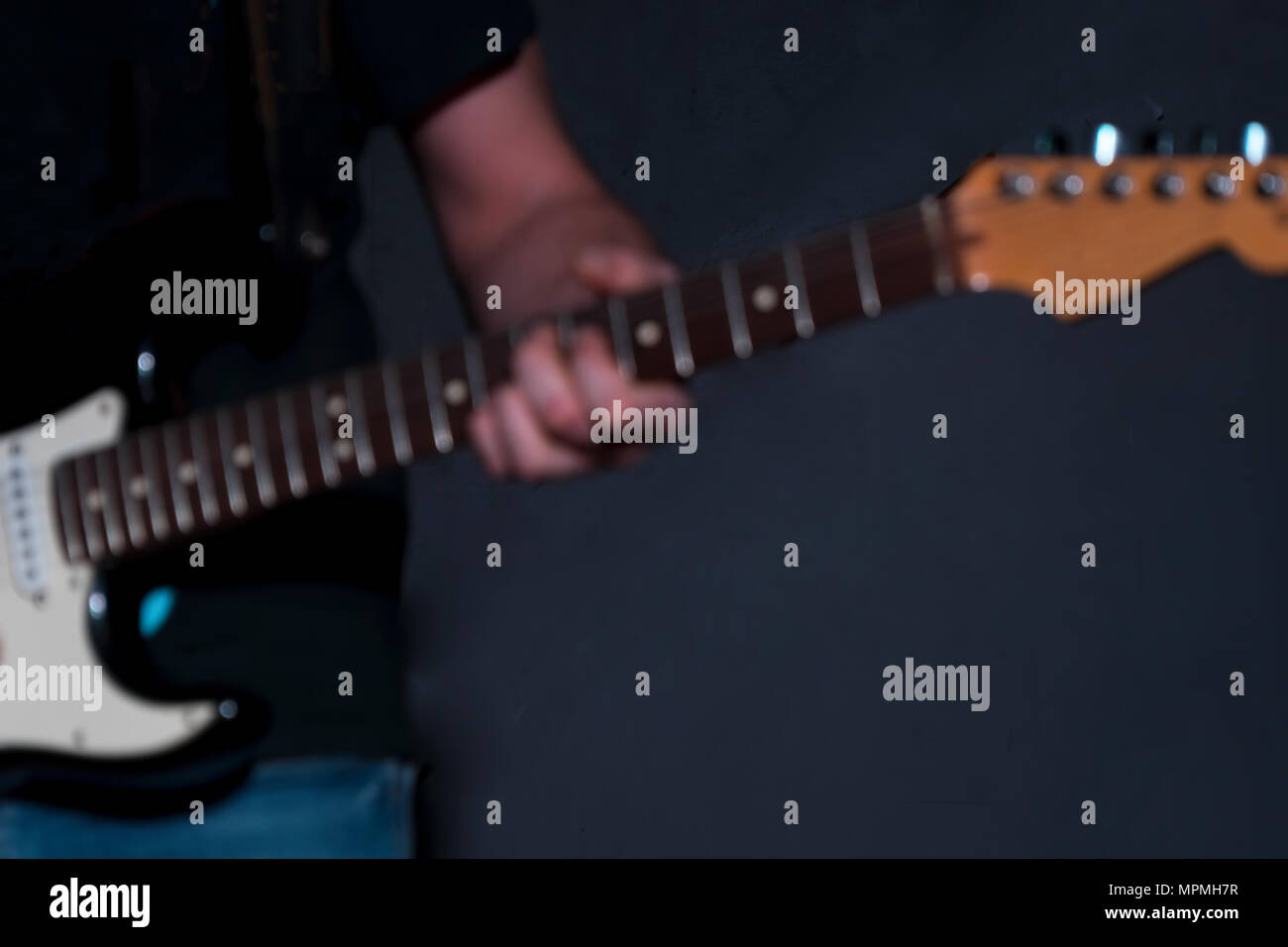 Immagine sfocata. Un lettore gitar con una chitarra in una stanza buia Foto Stock