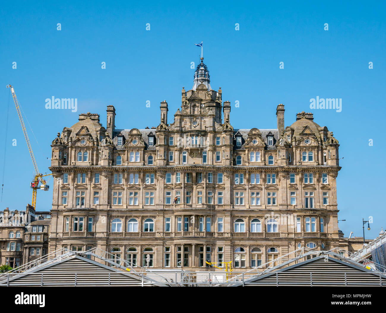Balmoral Hotel, Rocco Forte Hotel 5 stelle lusso, Princes Street, Edimburgo, Scozia con workmanin arancione la discesa in corda doppia Foto Stock