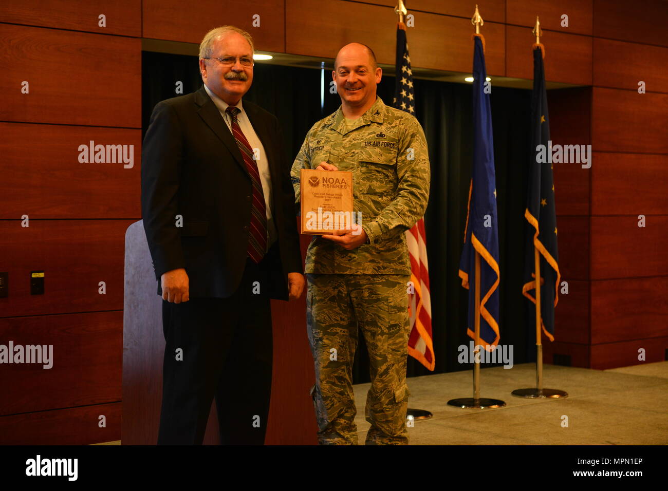 Doug Mecum, Vice Amministratore Regionale per la National Oceanic Atmospheric e di associazione della pesca in Alaska awards Air Force Col. George T.M. Dietrich III, il comandante JBER e 673d Air Base Wing Commander, una targa in riconoscimento della JBER essendo la loro specie in Spotlight eroe di recupero. NOAA ha scelto di riconoscere JBER prima a causa della efficacia della loro partnership in corso negli ultimi trent'anni. (U.S. Air Force foto di Senior Airman Kyle Johnson) Foto Stock