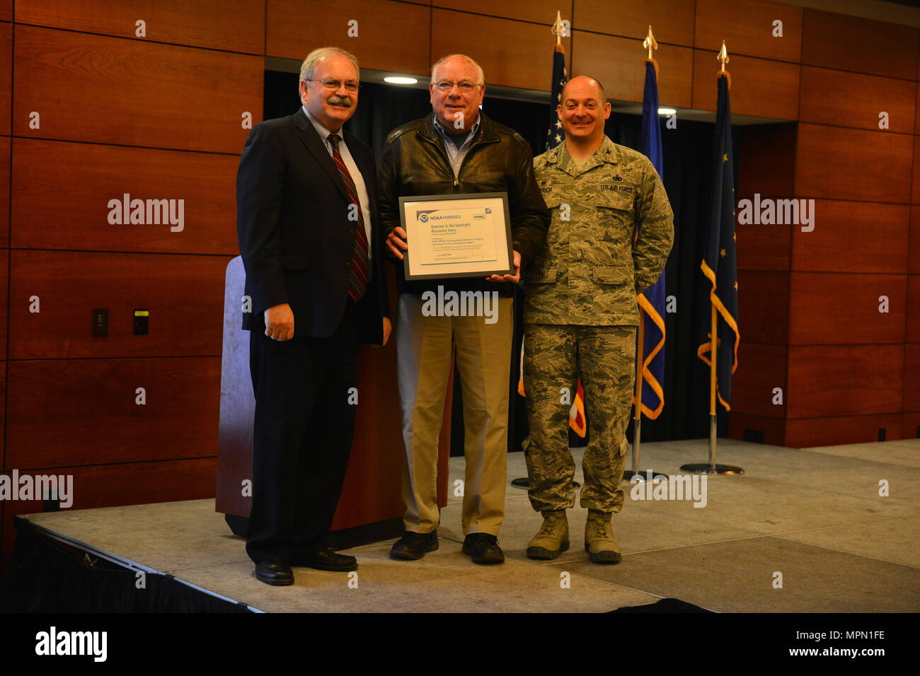 Doug Mecum, Vice Amministratore Regionale per la National Oceanic Atmospheric e di associazione della pesca in Alaska e Air Force Col. George T.M. Dietrich III, il comandante JBER e 673d Air Base Wing Commander awards Richard Graham, con la 673d' ingegnere civile squadrone una targa in riconoscimento della JBER essendo il NOAA le specie sotto i riflettori eroe di recupero. NOAA ha scelto di riconoscere JBER prima a causa della efficacia della loro partnership in corso negli ultimi trent'anni. (U.S. Air Force foto di Senior Airman Kyle Johnson) Foto Stock