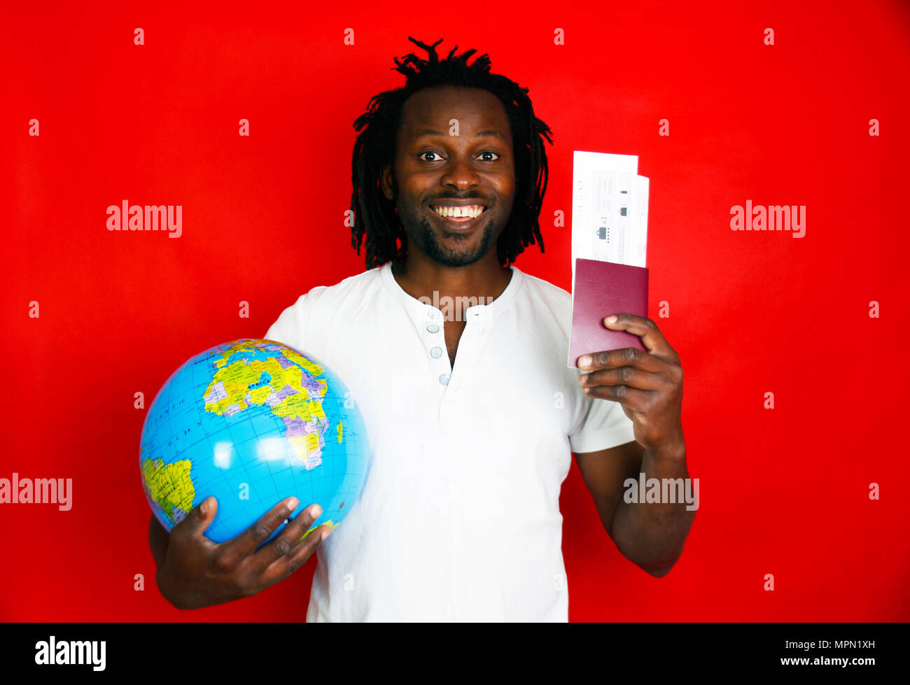 Eccitati e uomo felice tiene passaporti, biglietti e globo mondo nelle sue mani Foto Stock