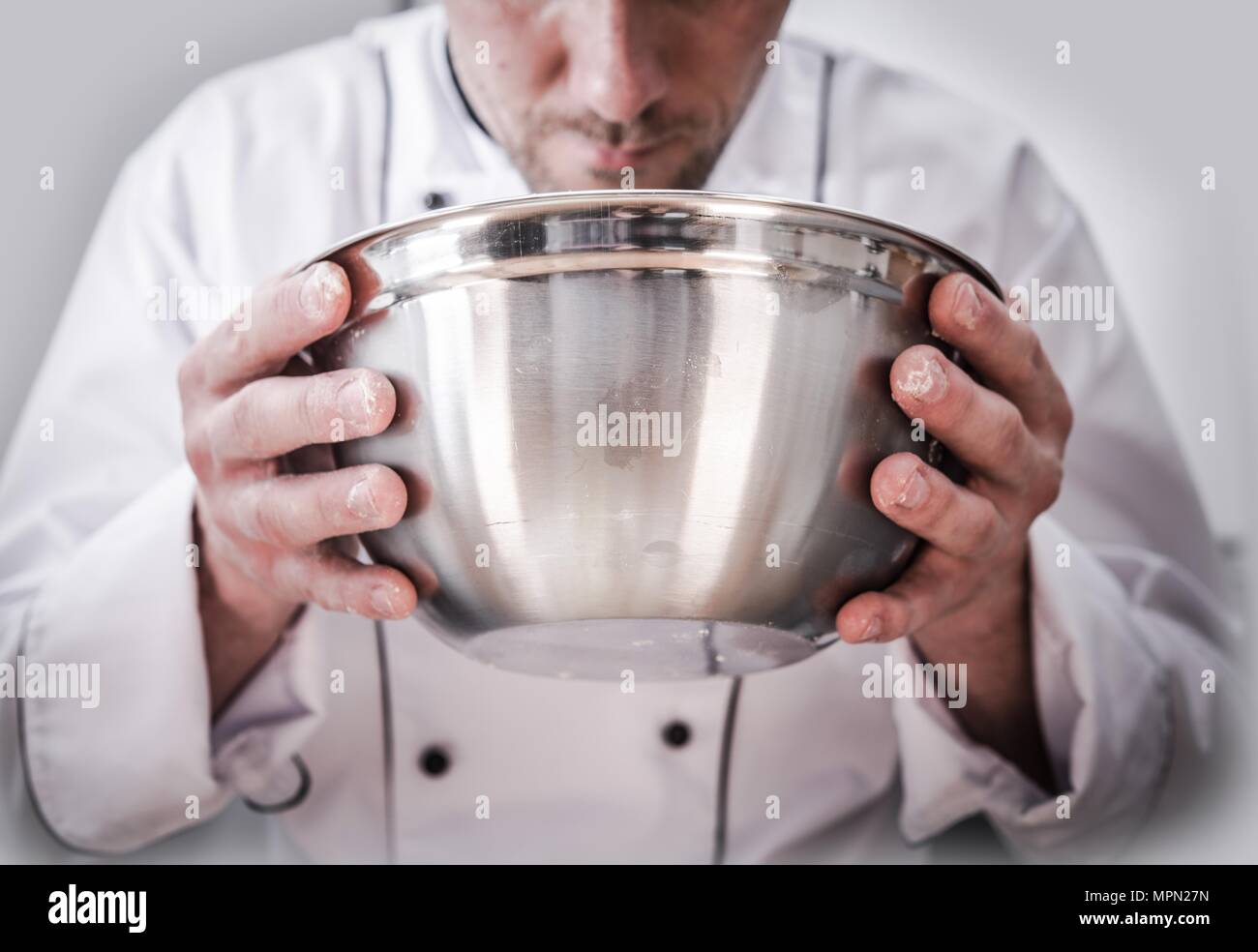 Chef di cucina il tempo di cottura. Lo Chef caucasici con ciotola di acciaio inossidabile in mani durante la preparazione del cibo. Foto Stock