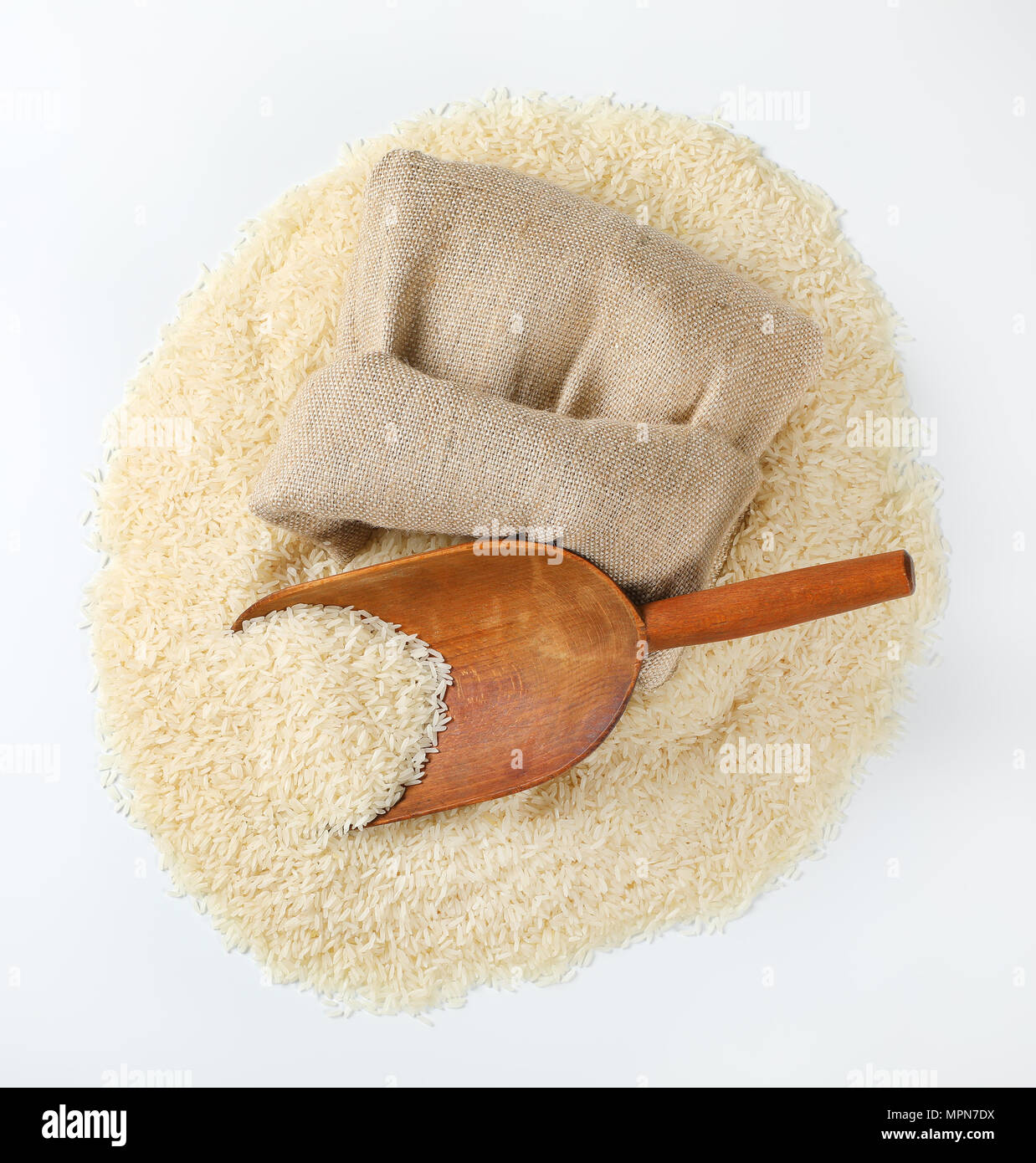 Pila di grana lunga riso, scoop di legno e tela borsa su sfondo bianco Foto Stock