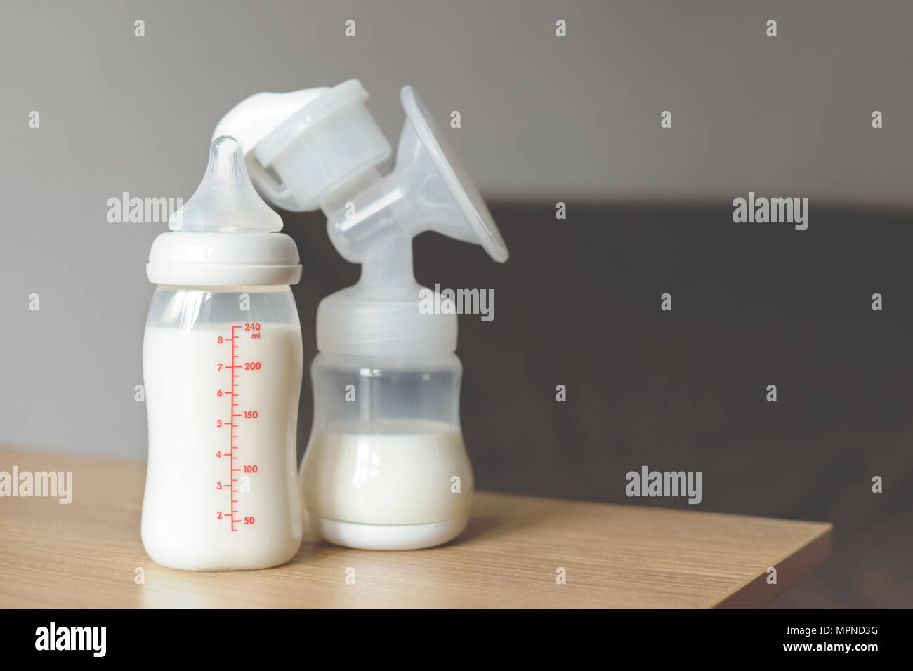 Tiralatte e bottiglia con latte materno sullo sfondo sfocato . La maternità e la cura del bambino concetto. Foto Stock
