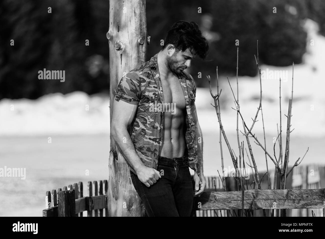 Sano giovane uomo in piedi forti muscoli di flessione mentre indossa jeans nero - Atletico muscolare Bodybuilder Modello di Fitness in posa all'aperto - un luogo fo Foto Stock