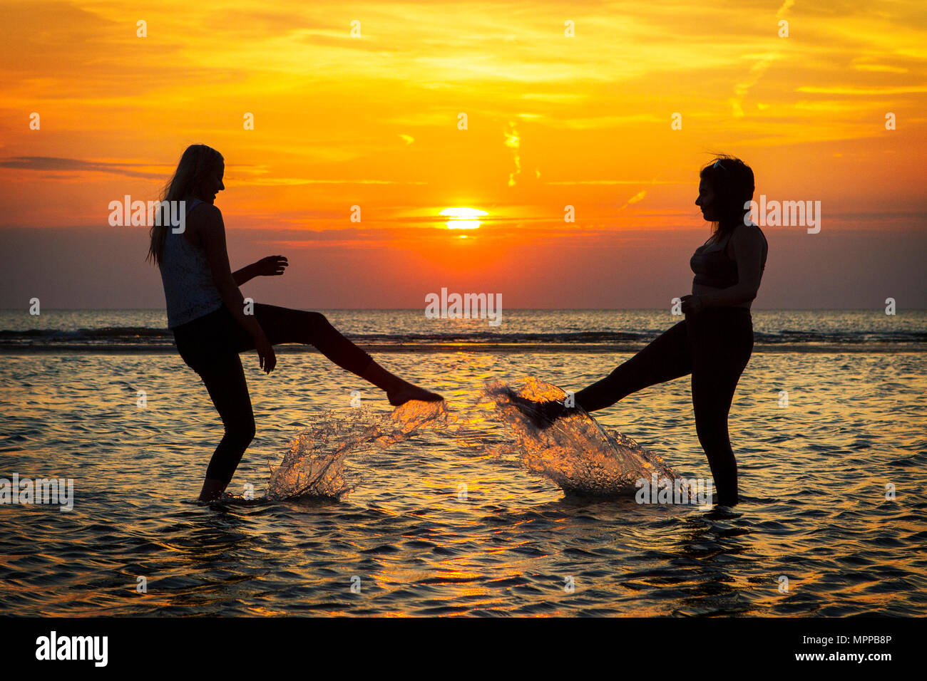 Southport, Merseyside. Il 24 maggio 2018. Regno Unito Meteo. Tramonto su Southport. Dopo uno dei giorni più caldi dell'anno finora, migliori amici Sarah Duberry & Jess Slinger divertirsi schizzi attraverso le acque di marea lungo il litorale di Southport beach nel Merseyside. Credito: Cernan Elias/Alamy Live News Foto Stock