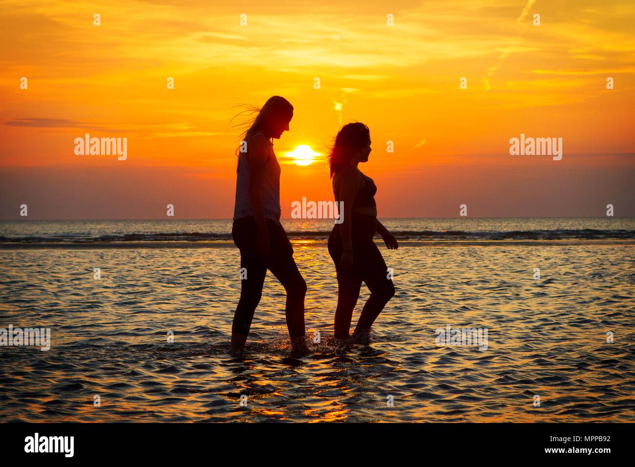 Southport, Merseyside. Il 24 maggio 2018. Regno Unito Meteo. Tramonto su Southport. Dopo uno dei giorni più caldi dell'anno finora, migliori amici Sarah Duberry & Jess Slinger divertirsi schizzi attraverso le acque di marea lungo il litorale di Southport beach nel Merseyside. Credito: Cernan Elias/Alamy Live News Foto Stock