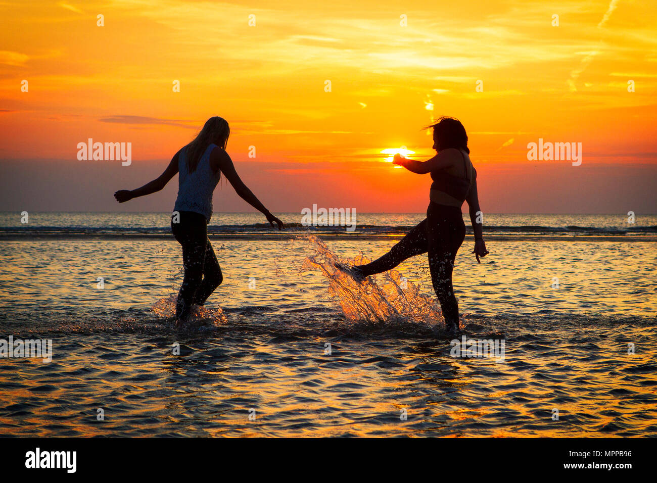 Southport, Merseyside. Il 24 maggio 2018. Regno Unito Meteo. Tramonto su Southport. Dopo uno dei giorni più caldi dell'anno finora, migliori amici Sarah Duberry & Jess Slinger divertirsi schizzi attraverso le acque di marea lungo il litorale di Southport beach nel Merseyside. Credito: Cernan Elias/Alamy Live News Foto Stock