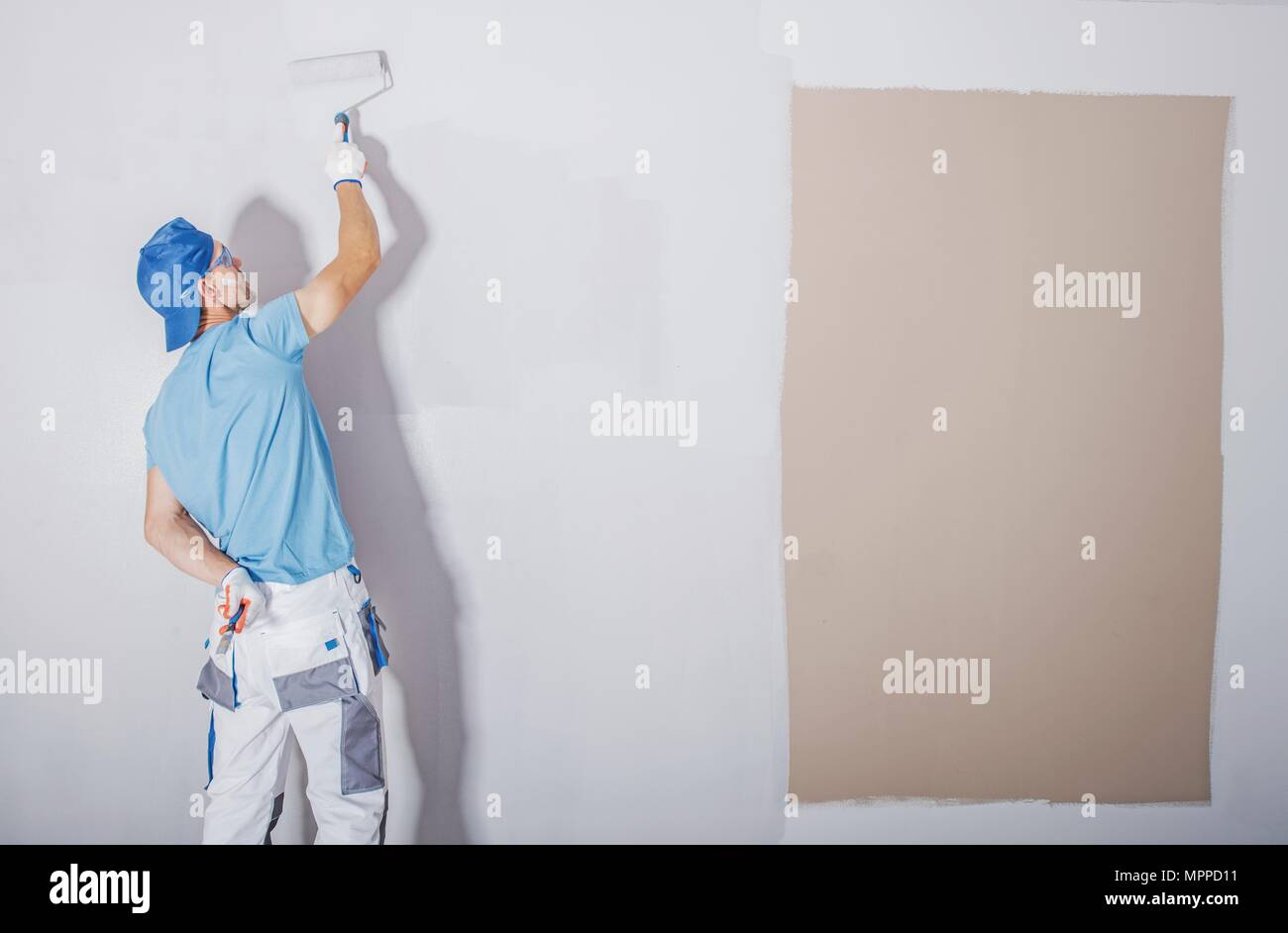 Camera pittore al lavoro. Copertura di tinta più scura da prodotti freschi e leggeri. Appartamento ristrutturato. Rinfrescare le pareti. Tema di costruzione. Foto Stock