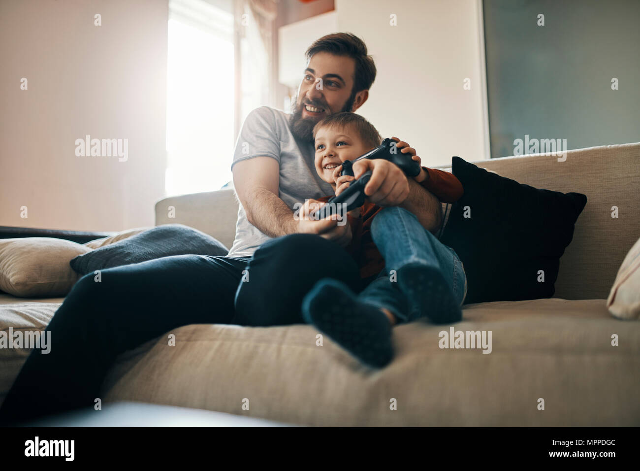Padre e figlio seduti insieme sul lettino la riproduzione di giochi per computer Foto Stock