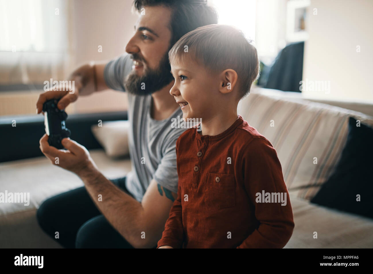 Felice piccolo ragazzo giocando gioco per computer con suo padre a casa Foto Stock