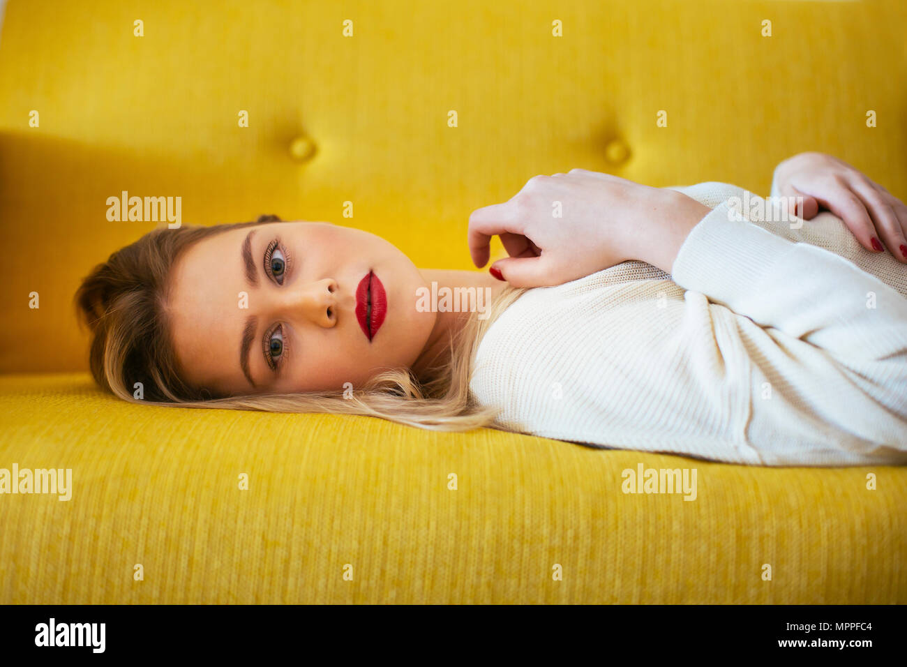 Donna bionda sdraiato sul divano Foto Stock