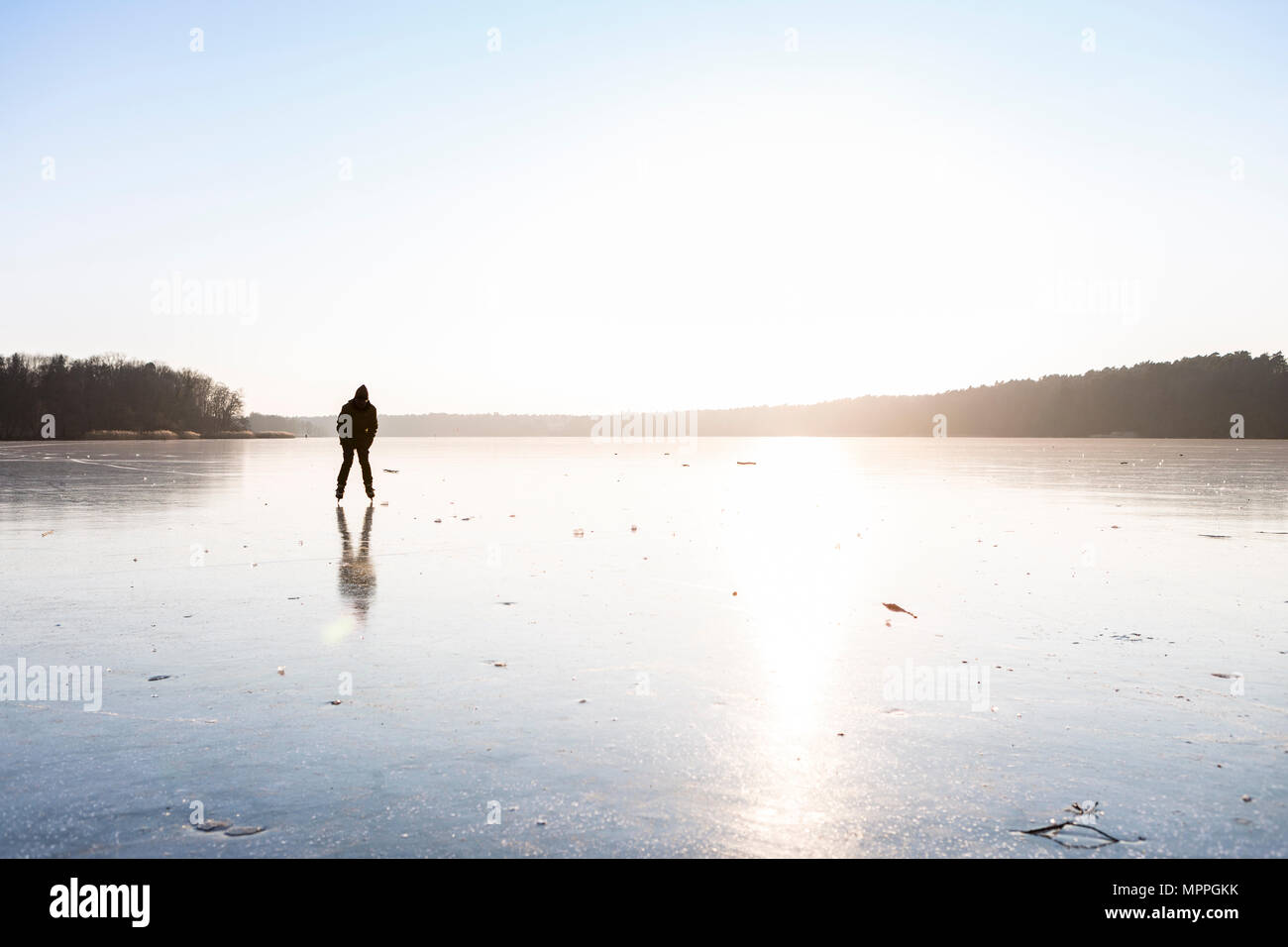 La Germania, il Land Brandeburgo, Lago Straussee, lago ghiacciato e la silhouette di un pattinatore su ghiaccio Foto Stock