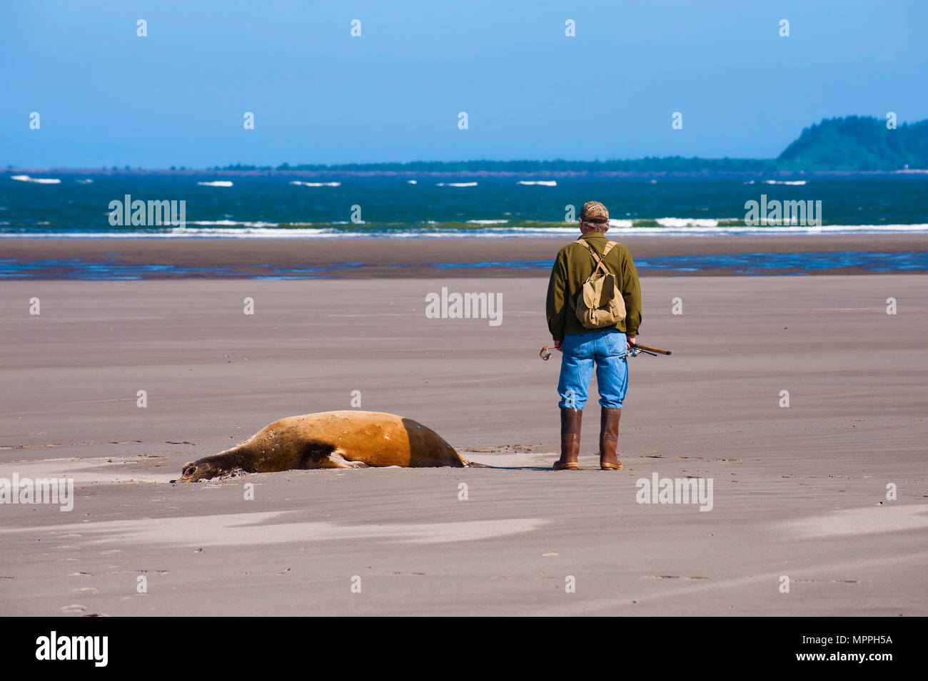 Warrenton, Oregon, Stati Uniti d'America - 30 Maggio 2014: un pescatore sta guardando fuori verso l'acqua, sulle rive del fiume Columbia dove incontra il Pacifico Foto Stock