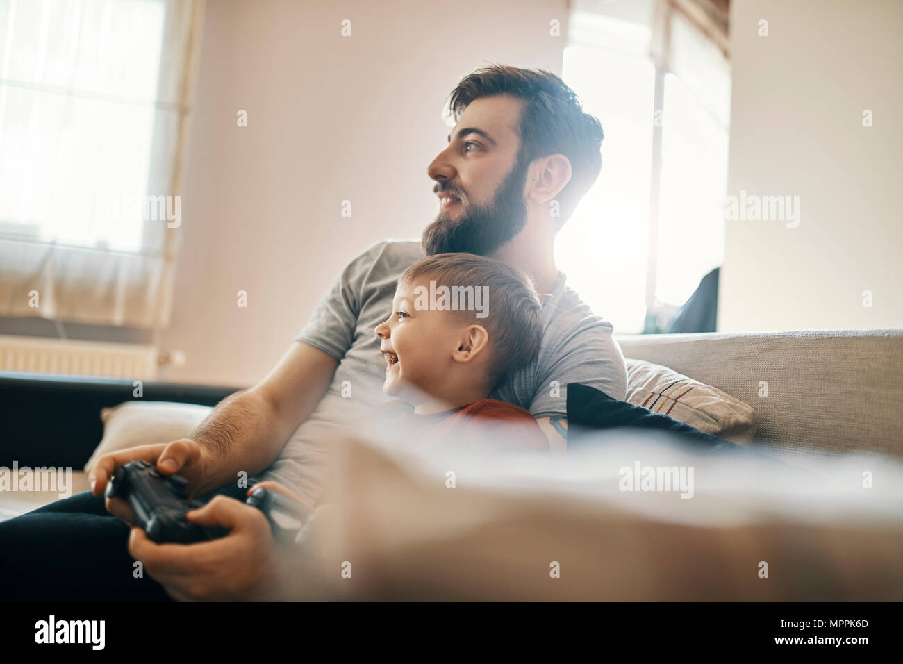Padre e figlio seduti insieme sul lettino la riproduzione di giochi per computer Foto Stock
