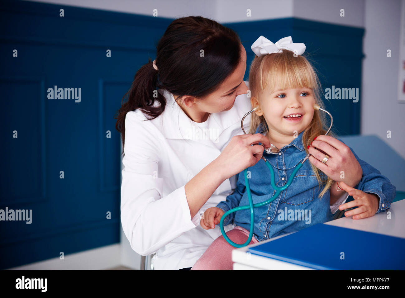 Medico e la ragazza che gioca con uno stetoscopio in pratica medica Foto Stock