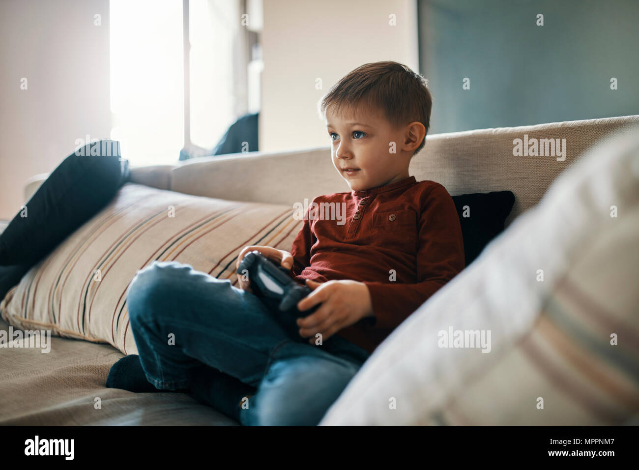 Ritratto di piccolo ragazzo seduto sul divano a giocare giochi per computer Foto Stock