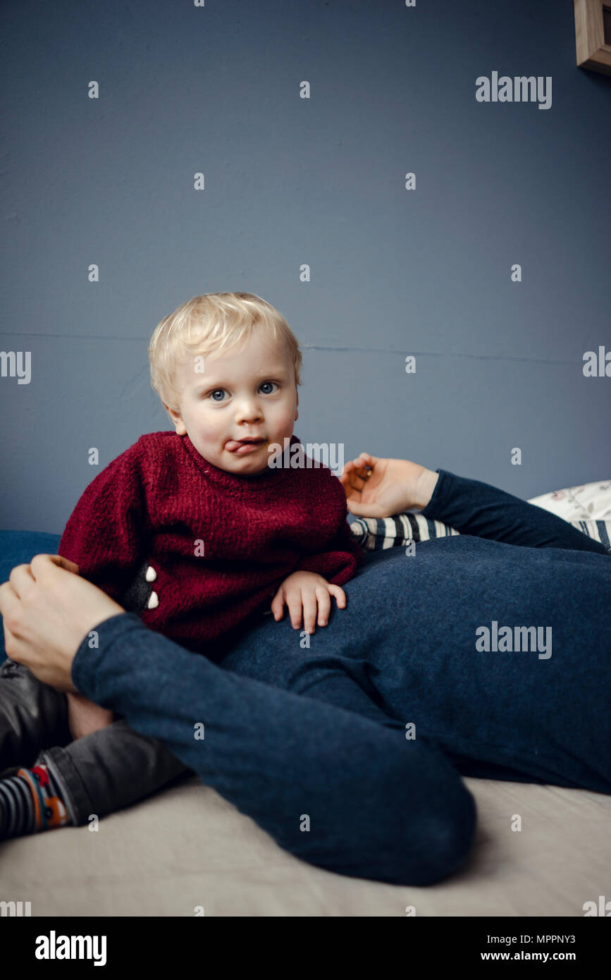 Padre e figlio in appoggio sul lettino, baby sitter sul volto del padre Foto Stock